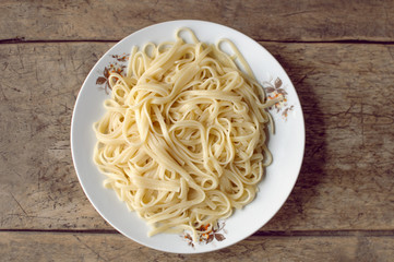 Spaghetti in a white bowl on a wooden surface