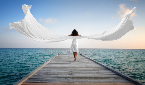 Sexy happy female model with white clothes standing on a jetty (