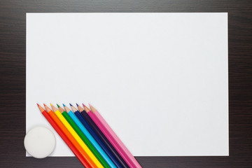 blank sheet of paper on the table with colorful pencils and rubber