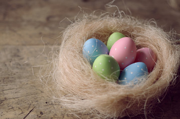 Easter eggs in nest on wooden background