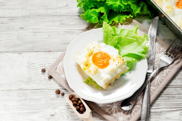
breakfast or lunch , air , beaten egg and baked in the oven , with lettuce and herbs on a white wooden background