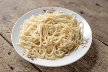 Spaghetti in a white bowl on a wooden surface