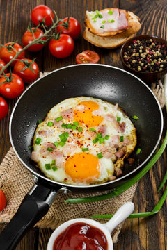 Fried eggs with in pan on wooden background.