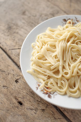Spaghetti in a white bowl on a wooden surface