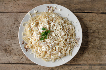 Spaghetti in a white bowl on a wooden surface