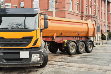 Ein grosser oranger LKW vor einem Haus aus roten Ziegelsteinen