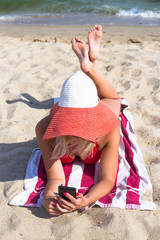Young pretty woman in red hat with phone relax near blue sea