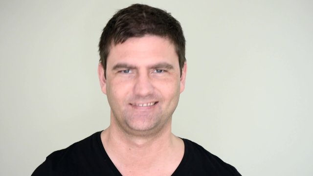 Serious and grumpy  man change his expression and start laughing.