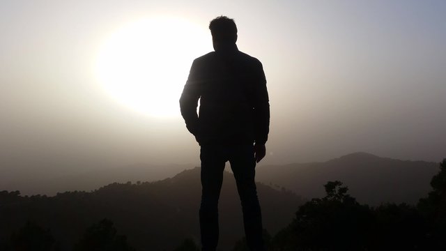 4K Man watching the sunset on the mountain 