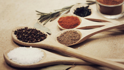 Various spices on kitchen spoons on grunge table