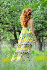 Fototapeta na wymiar young beautiful girl walks in the spring green apple orchard