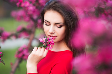 Happy beautiful young woman in blossom park with trees and flowers. 