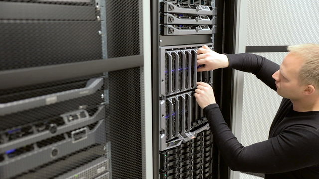 IT technician install harddrive in blade server in datacenter