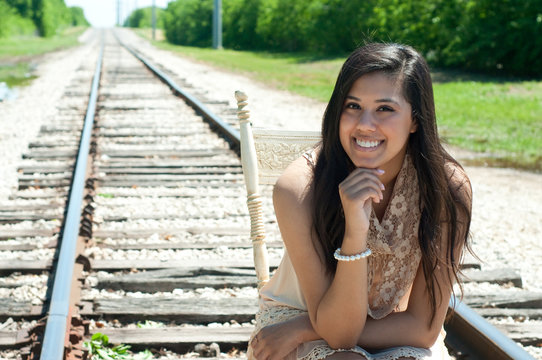 Beautiful senior girl sitting on train tracks.