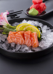 Salmon raw sasimi with ice on a black background