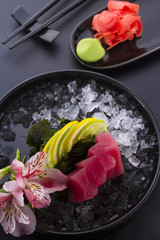 Tuna sashimi with ice on a black plate
