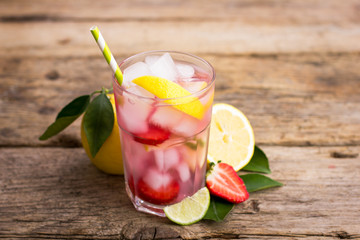 Homemade fresh pink lemonade with lemon, lime and strawberries