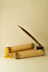 A scroll, inkwell with pen and lit candle