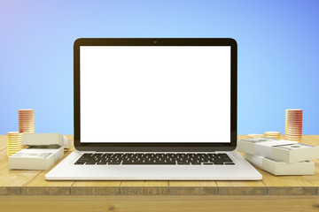 Blank white laptop screen on wooden table with stacks of coins a