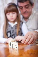 granddaughter and grandfather play dominoes