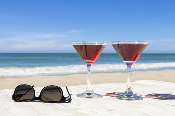 Two cocktails and sunglasses at a beach restaurant, tropical lei