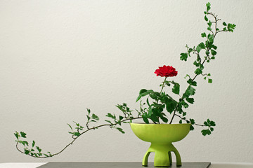 Ikebana mit roter Rose in gelber Vase
