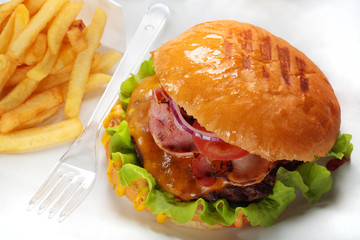 A burger, fries and fork on paper