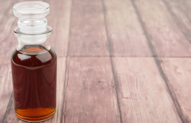 Maple vinegar in glass vial over wooden background