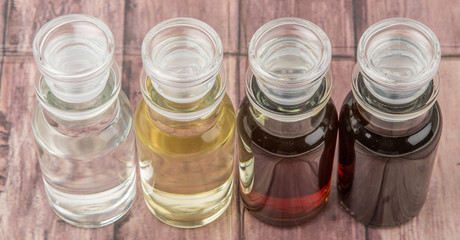 Vinegar, balsamic vinegar, maple vinegar and apple vinegar in glass vial over wooden background