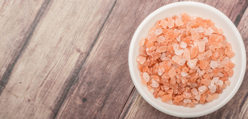 Himalaya or Himalayan rock salt in wooden bowl over wooden background