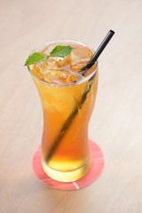 golden iced tea with black straw and mint