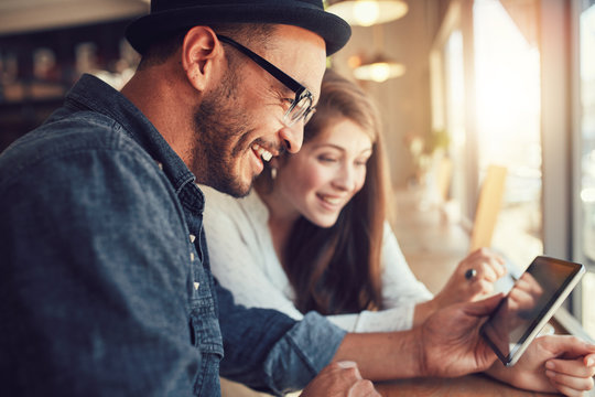 Young couple using a digital tablet together at a coffee shop - Powered by Adobe