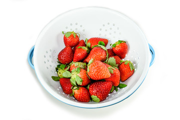 Isolated cleaning strawberries in the white enamel strainer