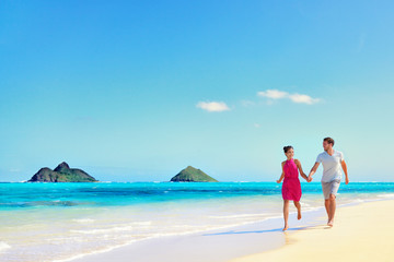 Hawaii vacation couple walking relaxing on white sand and pristine turquoise ocean water on...