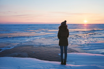 girl standing on a frozen Lake Baikal at sunset