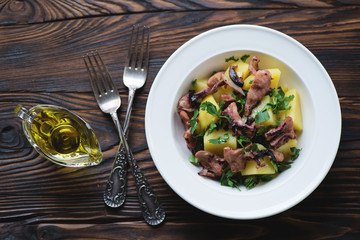 Above view of octopus salad with potato and parsley, close-up