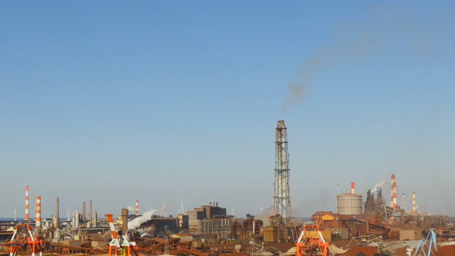 Industrial smoke rising in blue skies.