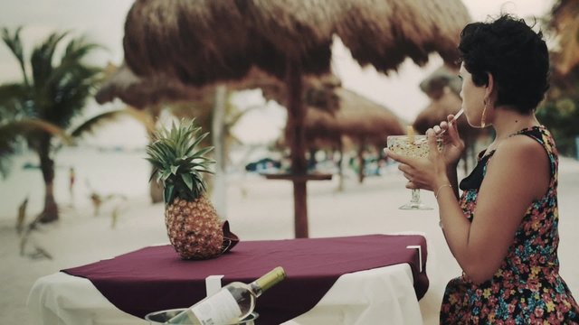 Hispanic Woman Having A Drink On A Restaurant In The Caribbean Beach