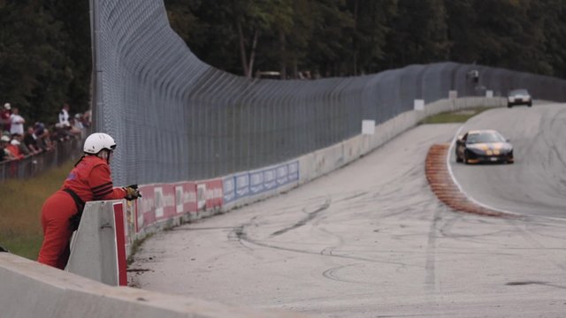 Worker of the track leans on the wall to watch the the race competition
