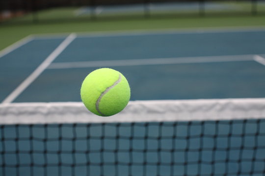 Tennis Ball Over Net on Blue Green Court