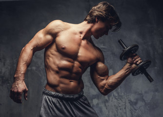 Fototapeta na wymiar Shirtless muscular guy doing biceps exercise.