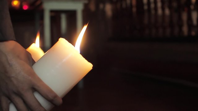 Believer holding a candle as wishing for a miracle inside church