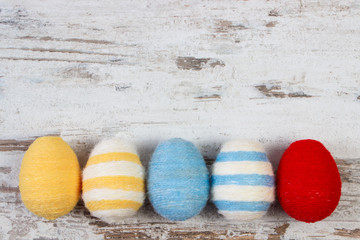 Easter eggs wrapped woolen string on wooden background, copy space for text, decoration for Easter