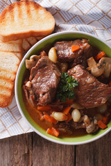 Beef Bourguignon close up in a bowl on the table. Vertical top view
