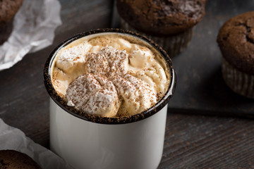 Cup of hot cocoa with marshmallows and chocolate muffins on the dark rustic wooden background