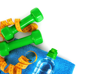 Dumbbells, tape measure and water bottle on the towel.