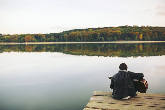 Young man playing on guitar at the lake