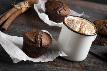 Cup of hot cocoa with marshmallows and chocolate muffins on the dark rustic wooden background