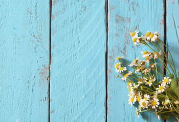 top view image of daisy flowers on blue wooden table. vintage filtered
