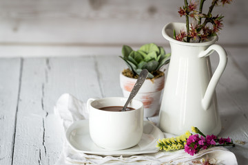 Still life of flowers in jar and cup with spoon